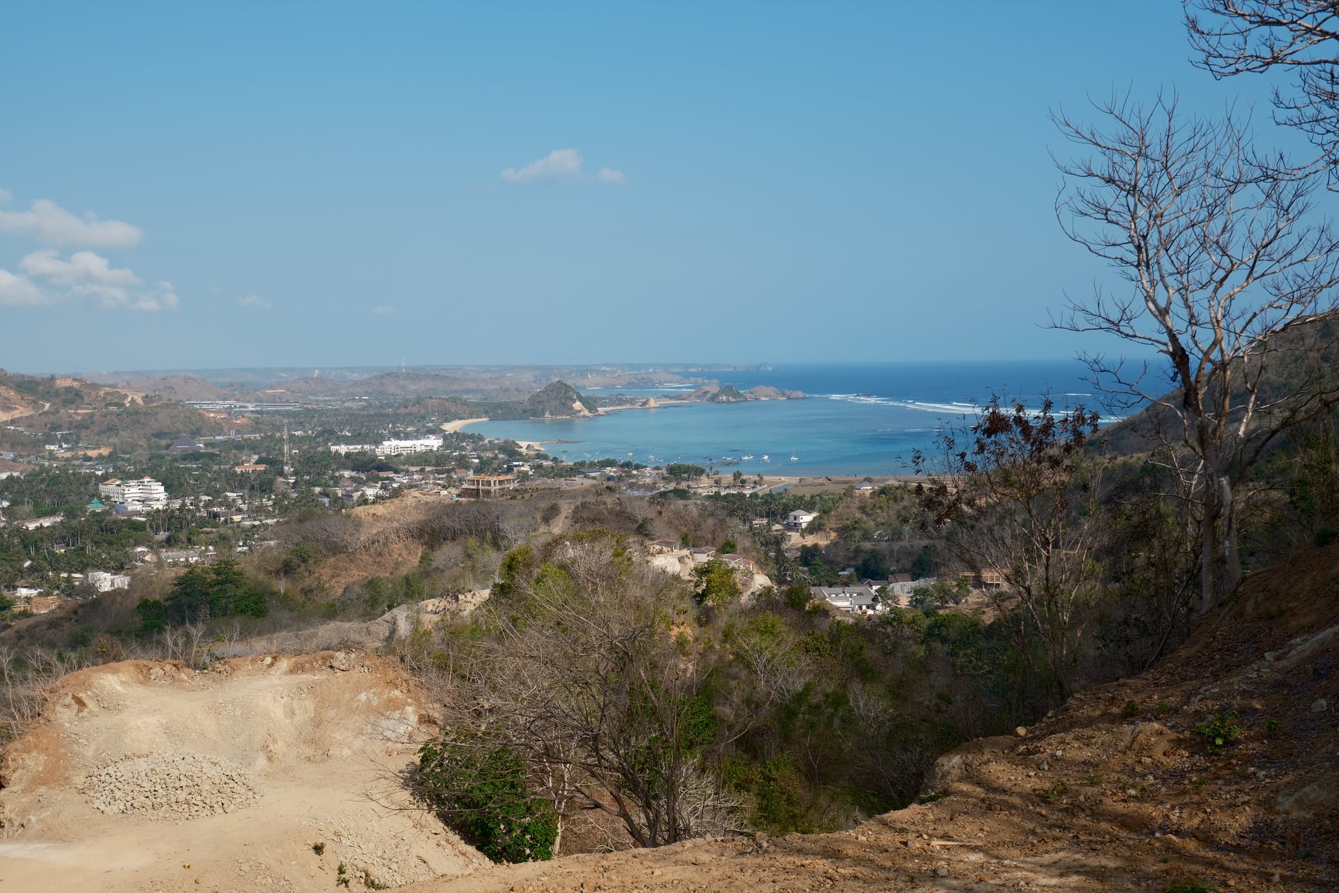 A coastal bay, surrounding hills and buildings seen from a hillside in Lombok